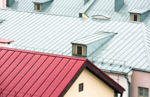 Standing seam metal roofing panels in light green and red with dormers