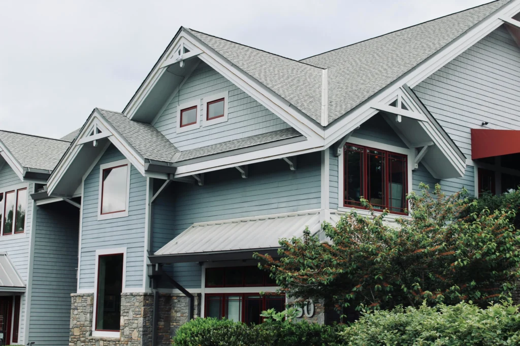 Home exterior with multiple gables and a grey asphalt shingle roof above a metal porch roof.