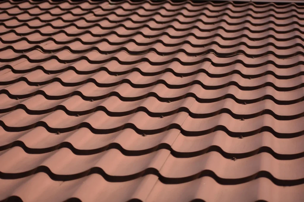 Close-up of brown metal roof panels with a tile-style pattern and exposed fasteners.