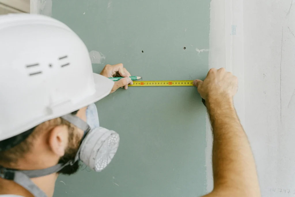 Contractor measuring a window opening with tape measure before replacement installation